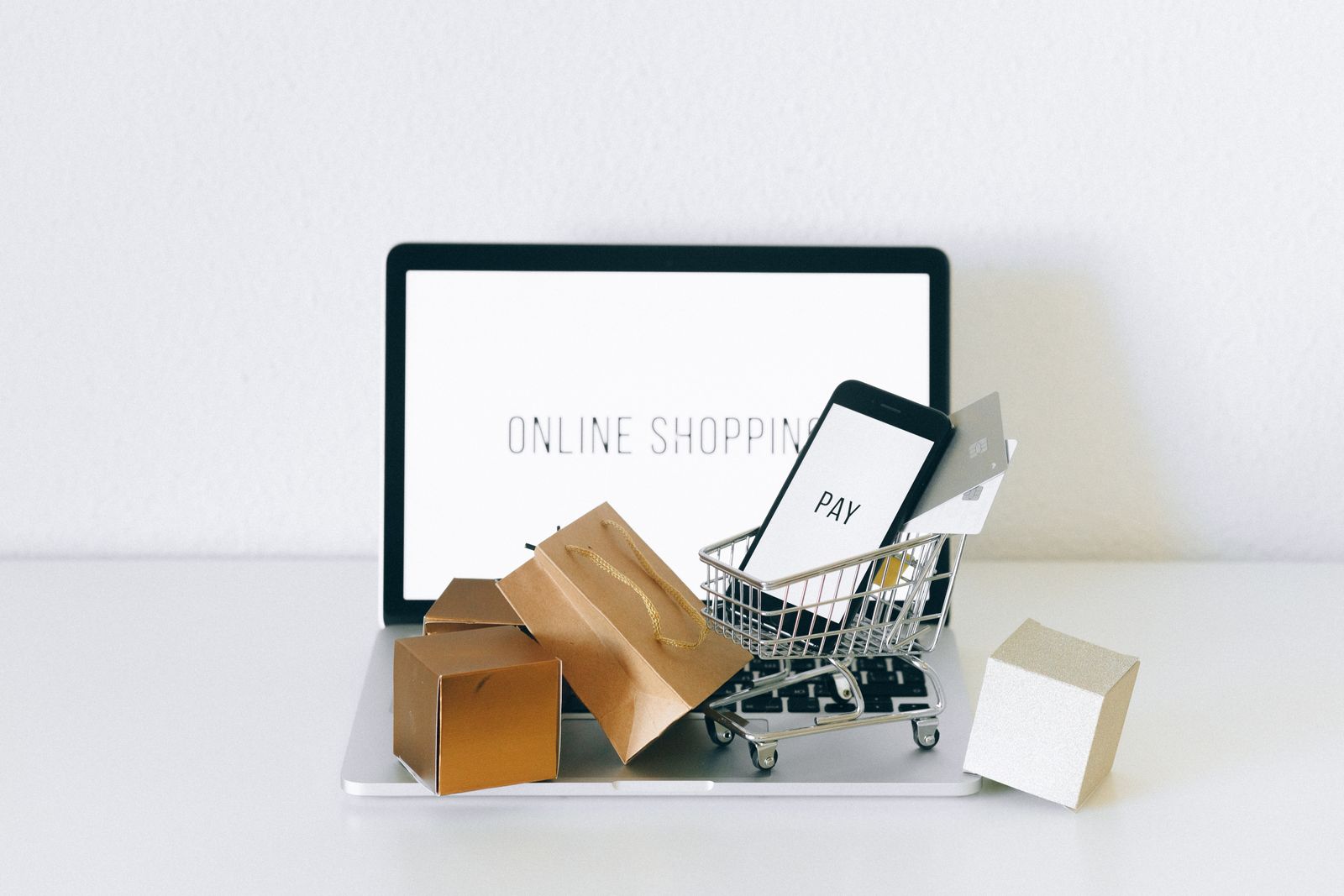 ECサイトでの買い物を表す写真。ノートPCとショッピングカートのミニチュア、段ボール箱